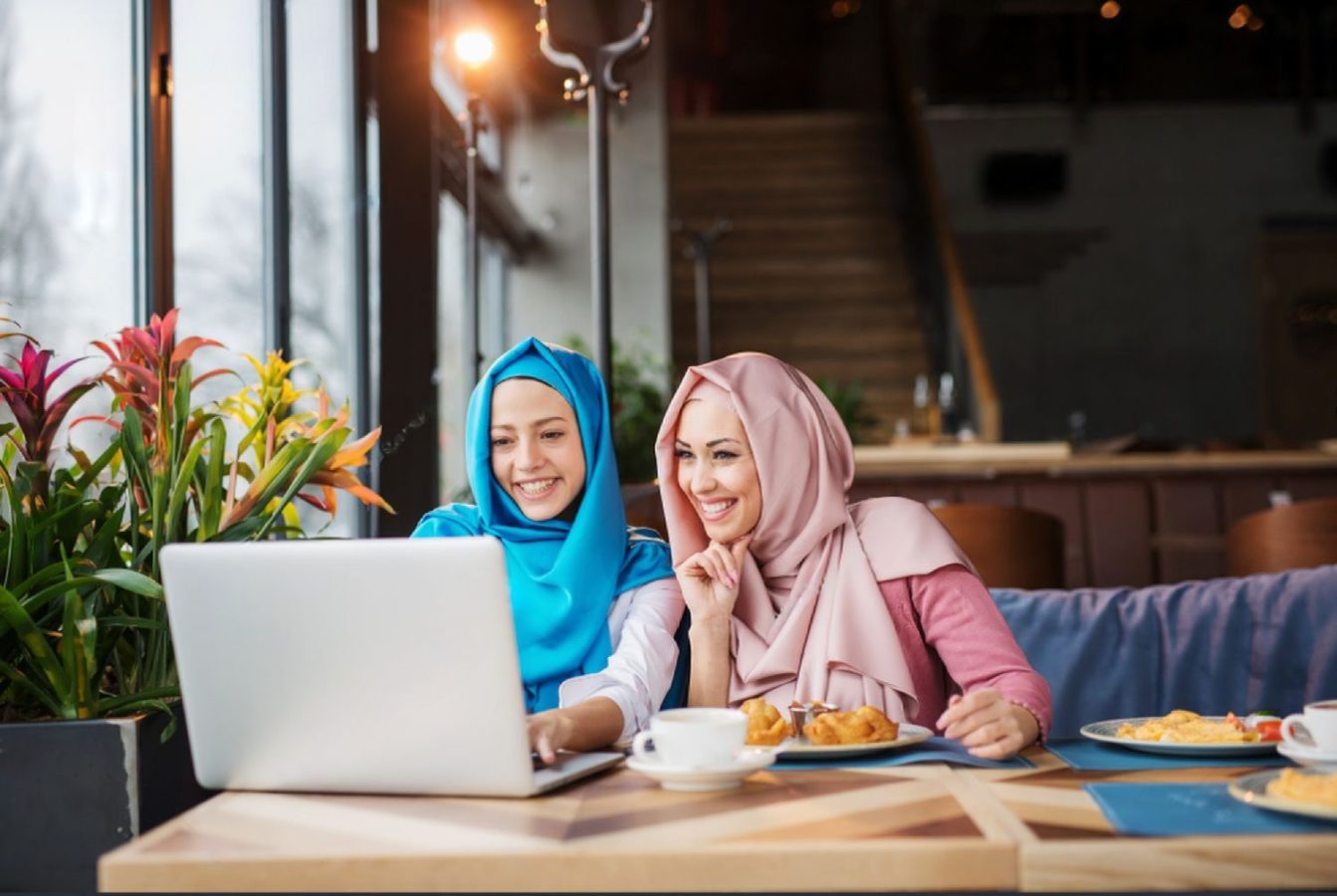 two hijabi women at a laptop